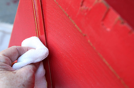 Rub furniture wax over the sanded areas to darken the exposed wood