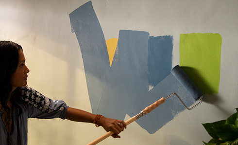 Person rolling blue paint on a wall